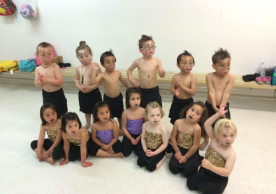 A group of young children dressed for a performance with moko drawn on their faces.