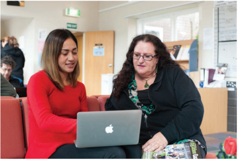 This image is a photo of two teachers discussing data from a laptop. 