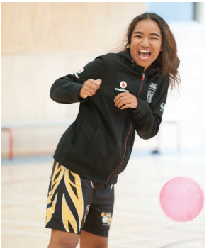 This image is a photo of a female student dodging a ball in the gym.